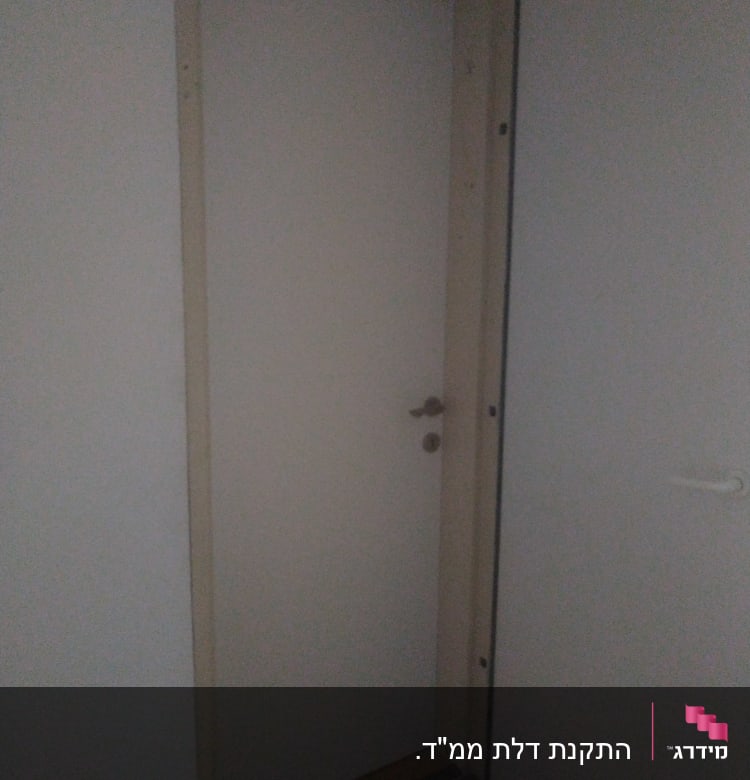 דלת לבנה עם ידית מתכת במסגרת עץ